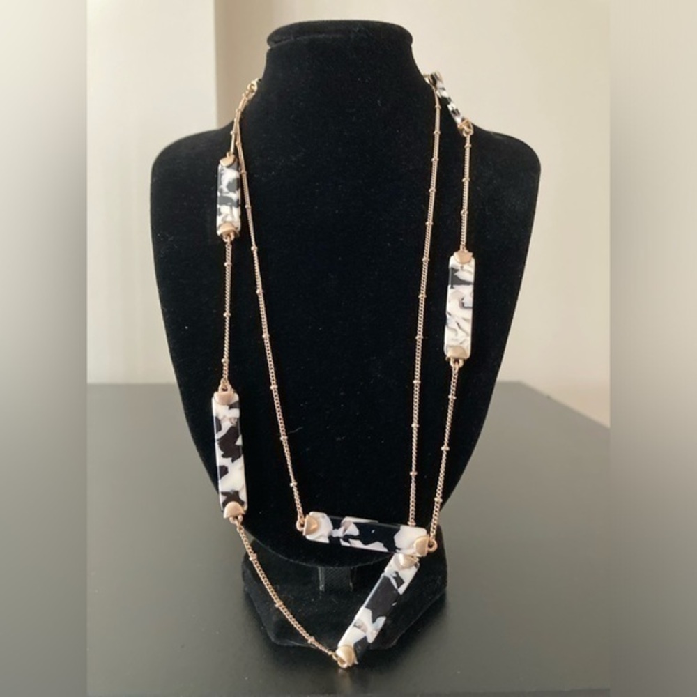Very long necklace with black and white needs on golden chain. Can be doubled up